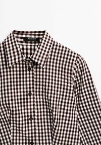 Chemise homme à manches longues avec boutons, motif à carreaux noir et blanc et col pointu, étiquette indiquant Massimo Dutti, fabriquée au Portugal.