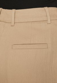 Pantaloni bej croiți dintr-un material texturat, având un singur buzunar la spate și bucle pentru curea pentru o ajustare confortabilă.