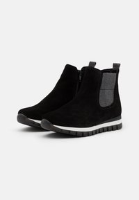 Černé antikované kotníkové boty z semiše s elastickými bočními panely, texturovanými šedými detaily, úchopovým tabem a bílou podrážkou s vroubkovaným vzorem.