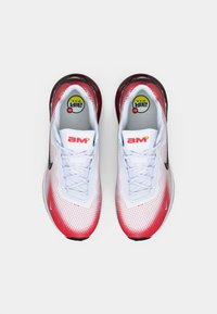Scarpe sportive bianche e rosse con una tomaia in rete, punta arrotondata, design con lacci e dettagli neri su suole e lati. Marchio Air Max visibile.