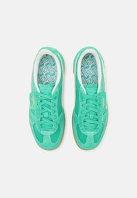 Baskets vertes en daim texturé et mesh, dotées de lacets blancs et d'une semelle intérieure à motifs avec une semelle extérieure en caoutchouc beige.