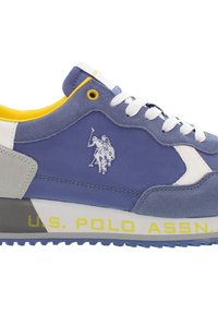 Zapatillas de ante azul con acentos de cuero blanco, forro amarillo y suela gris. Presenta un logotipo de un jugador de polo y el texto "U.S. POLO ASSN."
