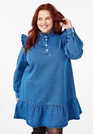 Vestido de mezclilla en azul claro con mangas largas, detalles fruncidos en los hombros, un dobladillo con volantes y una tapeta con botones en el escote.