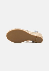 Espadrille avec une semelle en jute, semelle extérieure en caoutchouc texturé et sangles en tissu bleu doux. Design à talon plat pour plus de stabilité.