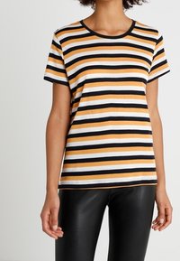 Pruhované tričko s horizontálními pruhy v oranžové, černé a bílé barvě. Krátké rukávy, kulatý výstřih, vyrobeno z měkké, lehké tkaniny.