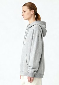 Felpa con cappuccio grigio chiaro con tasca frontale, polsini e orlo a coste. Realizzata in tessuto morbido con vestibilità comoda e senza motivi visibili.