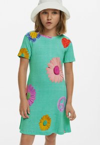En kortärmad klänning gjord av turkos tyg med flerfärgade blommor och hjärtan applikationer. Utsådd nederkant och ribbad textur.