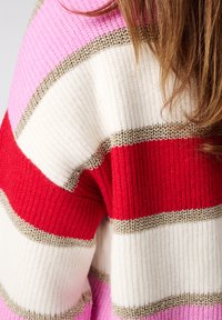 Gebreide trui met afwisselende strepen in rood, wit, roze en metalen gouden accenten; gestructureerde stof voegt diepte toe aan het ontwerp.