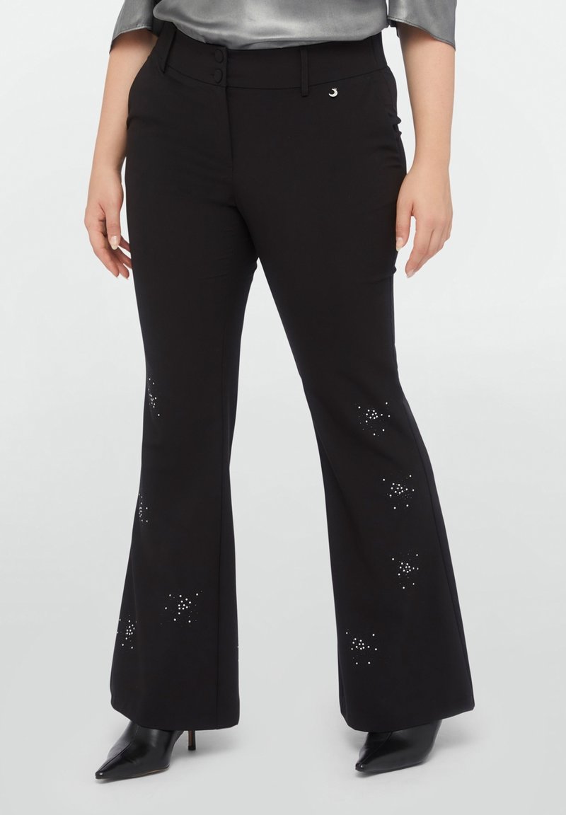 Black flared pants with a smooth texture, featuring silver embellishments arranged in star-like patterns, complemented by a high waistband and buttons.