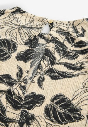 Tissu noir et blanc à motif de feuilles avec une surface texturée et nervurée ; présente une fermeture à bouton au niveau du cou à l'arrière.