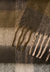 Smeđa i bež karirana vuna šal s resicama; mekan na dodir; sadrži različite nijanse i uzorke, uključujući tamnozeleni i svijetlosivi dijelove.
