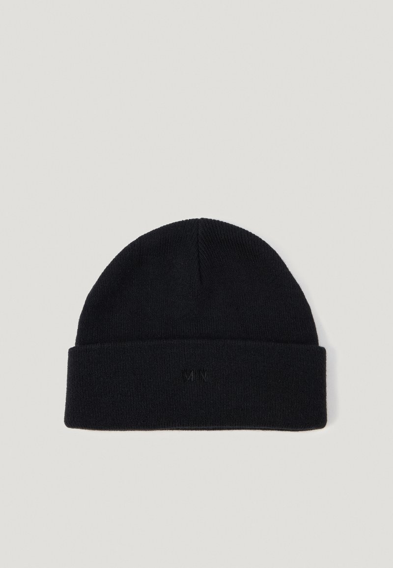 Juodas megztas beanie su lenktu kraštu, pagamintas iš švelnios medžiagos. Priekyje yra subtilus embosiuotas logotipo detalė. Lygi tekstūra.