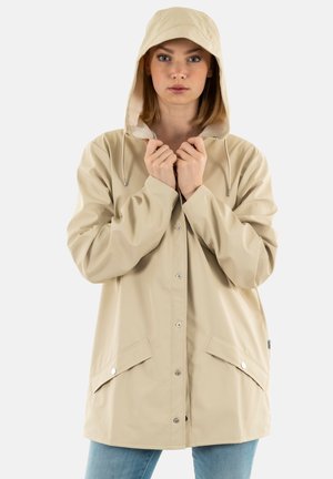 Veste de pluie beige avec capuche, fabriquée en matériau imperméable. Dispose de boutons-pression et de deux poches avant avec rabats. Texture lisse.