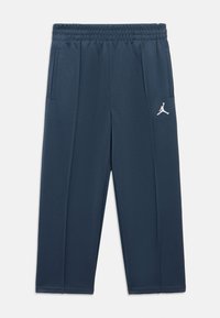 Pantaloni jogging bleumarin cu talie elastică, două buzunare laterale și un logo alb Jumpman pe partea superioară a coapsei. Material sintetic neted.