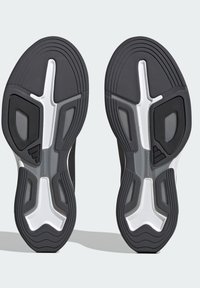Zwarte sportschoenzolen met een gemêleerd rubberpatroon, uniek profielontwerp en witte accenten voor stabiliteit en grip.
