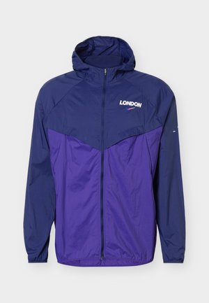 Ľahká kapucňová bunda v námorníckej modrej a fialovej farbe so zipsom vpredu a nápisom „LONDON“ s malým logom swoosh na hrudi.