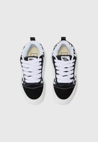 Svarta och vita sneakers med ett rutigt mönster, i mocka och canvasmaterial, vita snören och en rund gummisula.