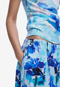 Cămașă și pantaloni cu un model floral albastru, confecționați dintr-un material ușor, având un elastic în talie și un detaliu cu șnur.