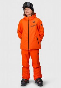 Leuchtend orangefarbene Skijacke und Skihose mit Reißverschluss vorne, zwei Seitentaschen und Logo-Details. Komplett mit Skibrille und Skischuhen.