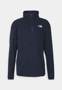 Marinblå fleece-pullover med hög krage och fjärdedelsdragkedja. Har den vita logotypen på vänster bröst och långa ärmar. Mjuk textur.