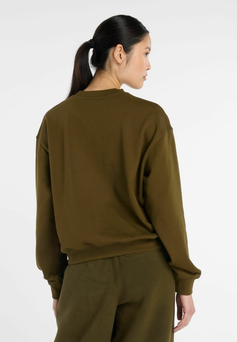 Sweat-shirt oversize vert olive à col rond et manches longues, en tissu doux, avec des détails de coutures subtiles et une coupe décontractée.