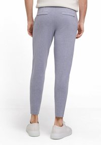 Helle graue, taillierte Hosen mit Gesäßtaschen, subtiler Textur und maßgeschneiderten Nähten, kombiniert mit weißen Sneakern.