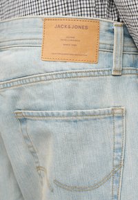 Ανοιχτό μπλε τζιν παντελόνι με κλασική εφαρμογή, που διαθέτει καφέ δερμάτινη ετικέτα στη μέση και πίσω τσέπη με συνηθισμένο ράψιμο.