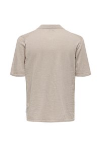 Camisa polo corta de manga beige vista desde atrás con una pequeña etiqueta blanca en la costura lateral izquierda.