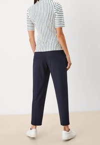Top de manga corta a rayas en blanco y azul marino, combinado con pantalones azul marino y zapatillas blancas. Presenta un corte ajustado y una textura de tela suave.