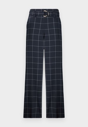 Pantaloni în carouri bleu marin, cu un design cu picioare largi, având un brâu cu o cataramă metalică circulară și linii albe pe un material neted.