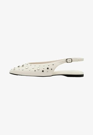 Witte platte slingback schoen met zwarte zool, puntige neus, zilveren en zwarte studs als versiering en verstelbare zijriem met gesp.