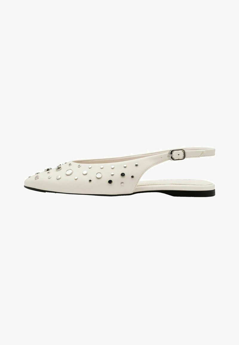 Chaussure plate blanche à bride arrière avec semelle noire, bout pointu, ornements à clous argentés et noirs, et bride latérale réglable avec boucle.
