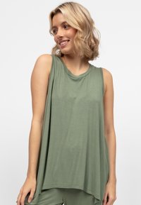 Zielona bezrękawnik o luźnym fasonie, prążkowanej fakturze i okrągłym dekolcie, z asymetrycznym dołem dla dodatkowego akcentu.