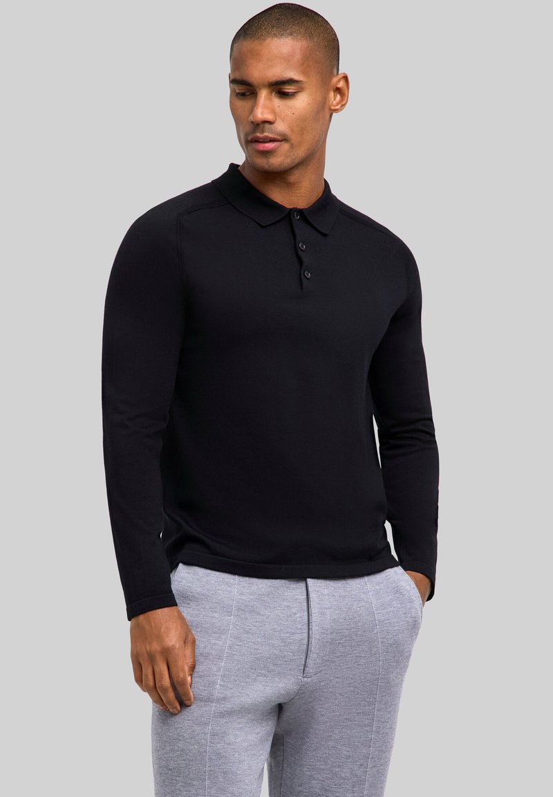 Czarna koszulka polo z długim rękawem, kołnierzykiem i trzema guzikami, zestawiona z szarymi dresami o gładkiej fakturze.