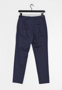 Pantaloni blu navy realizzati in tessuto liscio, con un design elegante caratterizzato da pieghe frontali e una tasca posteriore singola.