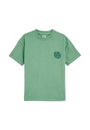 Camiseta de algodón verde con cuello redondo, mangas cortas y un logo circular en verde más oscuro en el pecho. Diseño simple.