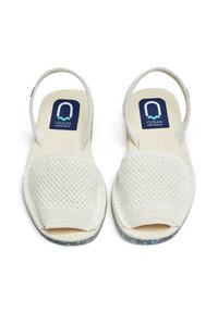 Sandalias blancas de punta abierta con una parte superior de malla texturizada, plantilla acolchada y una suela clara con un sutil patrón azul.