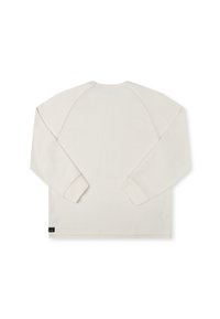Long-sleeve top in beige textured fabric with raglan sleeves, flat seams, and a small logo tag at the hem. Simple and clean design.
