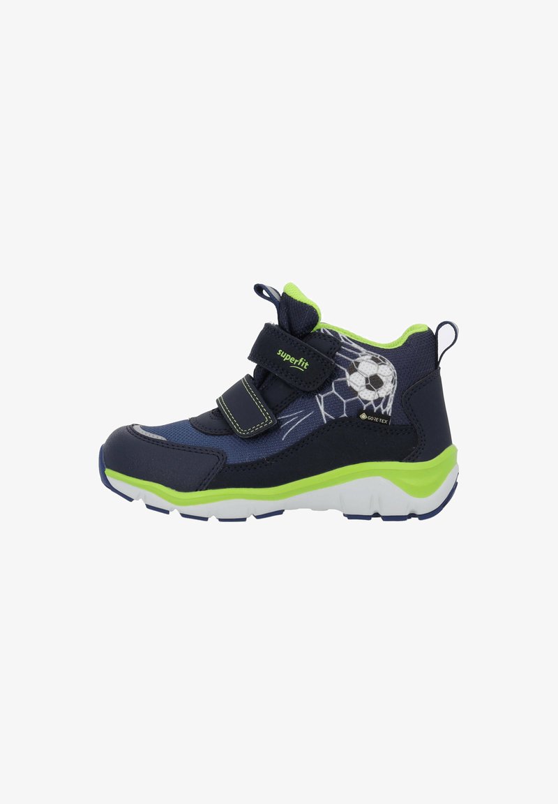 Zapatos infantiles de color azul marino con detalles en verde, material sintético, doble tira de Velcro y un gráfico de un balón de fútbol en el lateral.