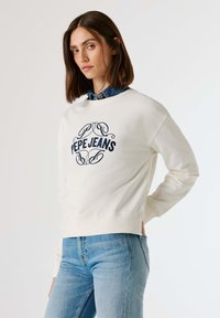 Φούτερ σε κρεμ χρώμα με σκούρο μπλε λογότυπο "Pepe Jeans", στρογγυλή λαιμόκοψη και ριμπ μανσέτες. Συνδυασμένο με ανοιχτό μπλε τζιν. Ομαλή υφή.