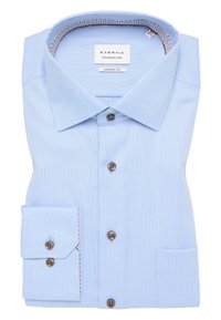 Camicia azzurra chiara piegata ordinatamente, con un tessuto strutturato, colletto button-down e bottoni marroni. Include una tasca sul petto.