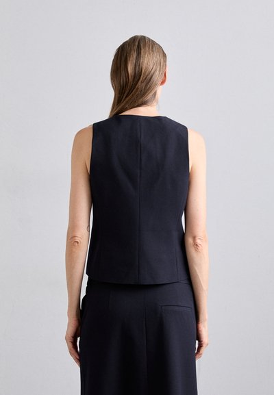 Navy sleeveless top made from smooth fabric, featuring a clean design, straight edges, and a slightly curved hem at the back.