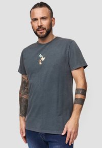 Grijze katoenen t-shirt met korte mouwen, voorzien van een kleine cartoonfiguur op de borst. Klassiek ronde hals ontwerp.