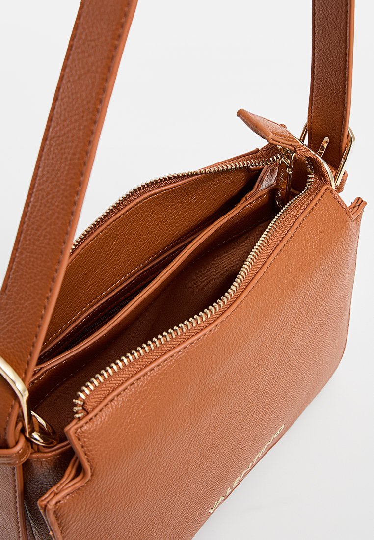 Sac à main en cuir marron avec une surface texturée, comportant une fermeture éclair et plusieurs compartiments intérieurs. Accents en matériel doré visibles.