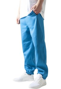 Pantaloni de jogging de culoare albastru deschis, dintr-un material moale, cu talie elastică și manșete. Purtați cu pantofi sport albi.