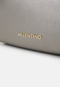 Siva teksturirana usnjena torba z zlatim logotipom "Valentino". Gladka površina z rahlim leskom in minimalističen dizajn.