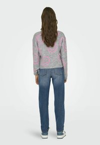 Szary sweter z różowym wzorem uśmiechniętej buźki, z prążkowanymi mankietami i ściągaczem; połączony z luźnymi niebieskimi dżinsami i jasnymi sneakersami.