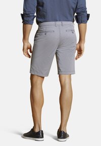 Shorts gris à carreaux pour homme avec une coupe ajustée, dotés de poches arrière et d'une texture lisse, associés à des baskets noires.