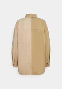Chemise à manches longues boutonnée avec un design divisé en beige clair à gauche et beige foncé à droite, vue de dos.