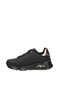 Chaussure de sport noire avec une tige synthétique lisse, des accents perforés, des œillets dorés et un détail de talon en rose doré métallisé. Comprend un système d'amorti.